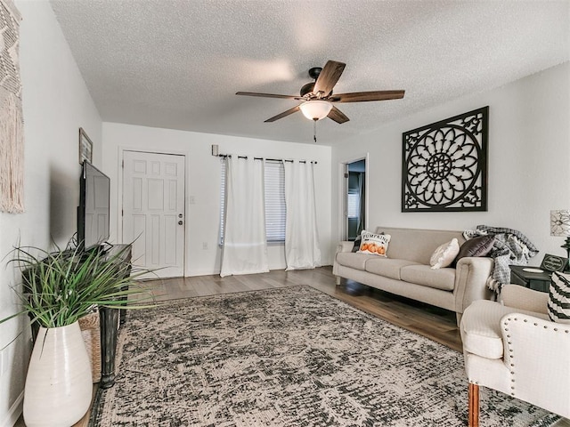 living room featuring ceiling fan, a textured ceiling, and wood finished floors