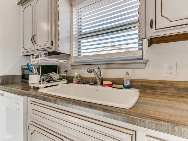 kitchen with dishwasher, dark countertops, and a sink