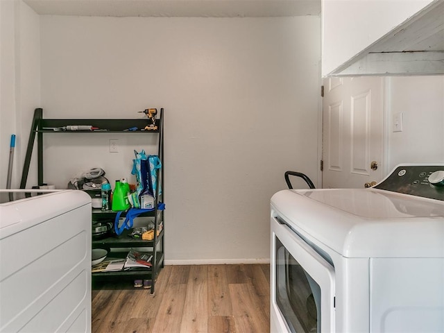 laundry area with washing machine and dryer, laundry area, baseboards, and wood finished floors