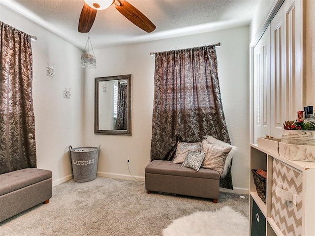 living area with a textured ceiling, carpet floors, a ceiling fan, and baseboards