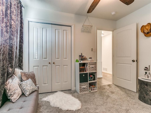 interior space with a ceiling fan, visible vents, a textured ceiling, and carpet flooring