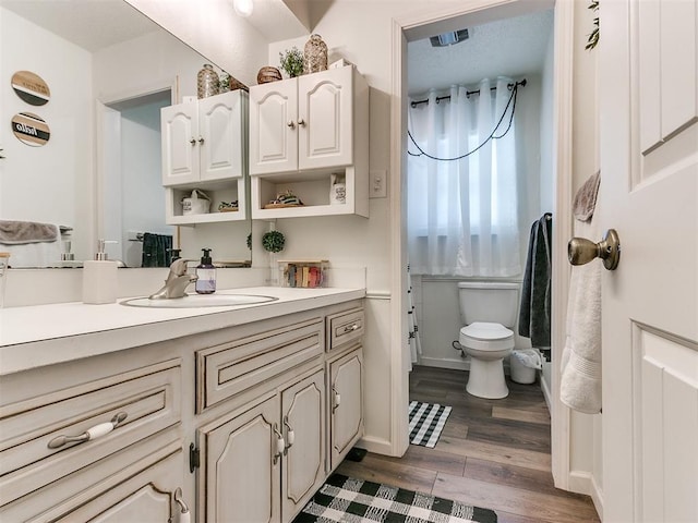 bathroom with vanity, wood finished floors, toilet, and baseboards