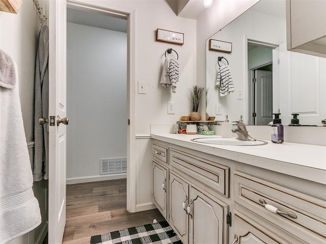 bathroom with baseboards, visible vents, wood finished floors, and vanity