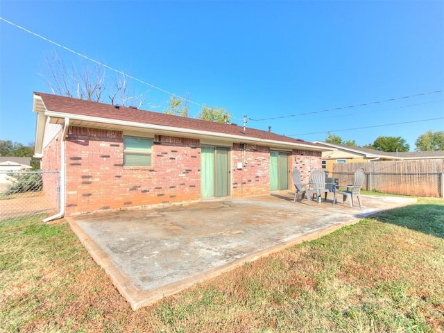 back of property featuring a patio area, a yard, fence, and brick siding