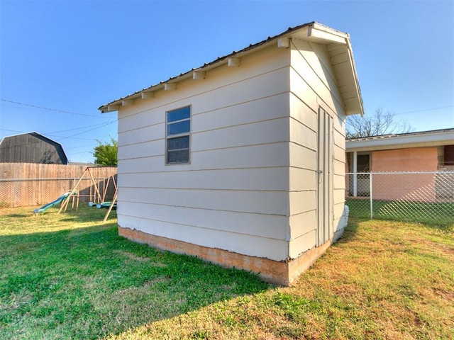 view of side of property with an outbuilding, a fenced backyard, and a lawn