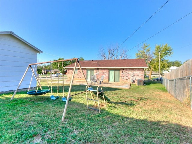 back of property with central air condition unit, fence, a playground, and a yard