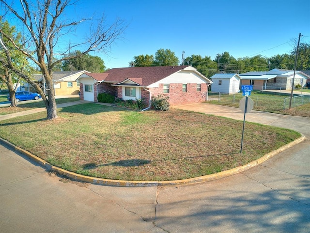 ranch-style home featuring brick siding, fence, concrete driveway, and a front yard