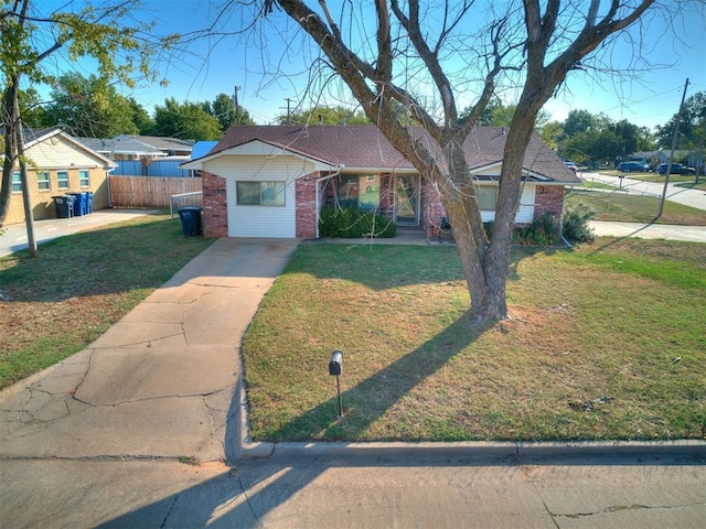 view of front facade with a front lawn, fence, and brick siding