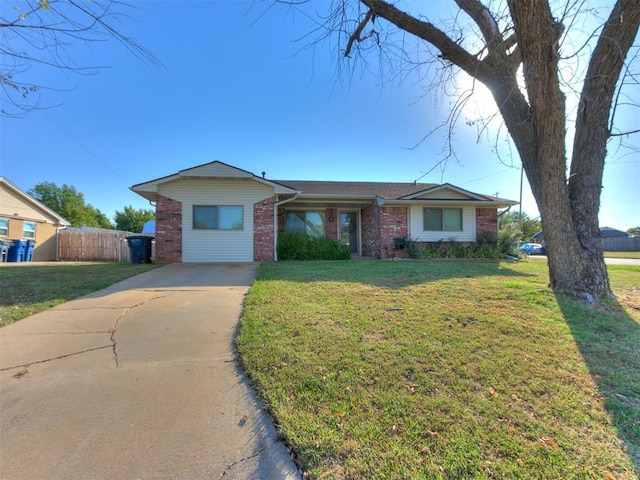 ranch-style home featuring a front yard, fence, concrete driveway, and brick siding