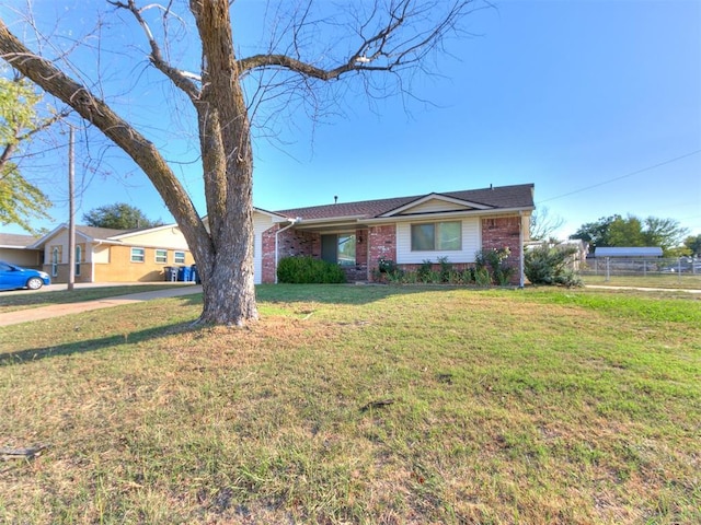 ranch-style house featuring a front yard, fence, and brick siding