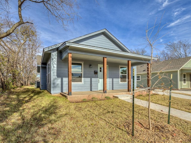 view of front of house with a porch, concrete driveway, central AC unit, a garage, and a front lawn