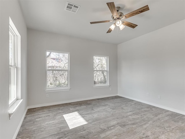 unfurnished room with ceiling fan, wood finished floors, visible vents, and baseboards