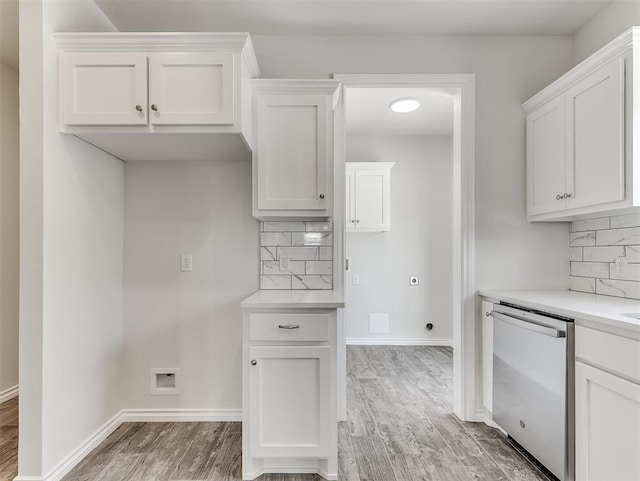 kitchen featuring light countertops, stainless steel dishwasher, light wood-type flooring, and white cabinetry