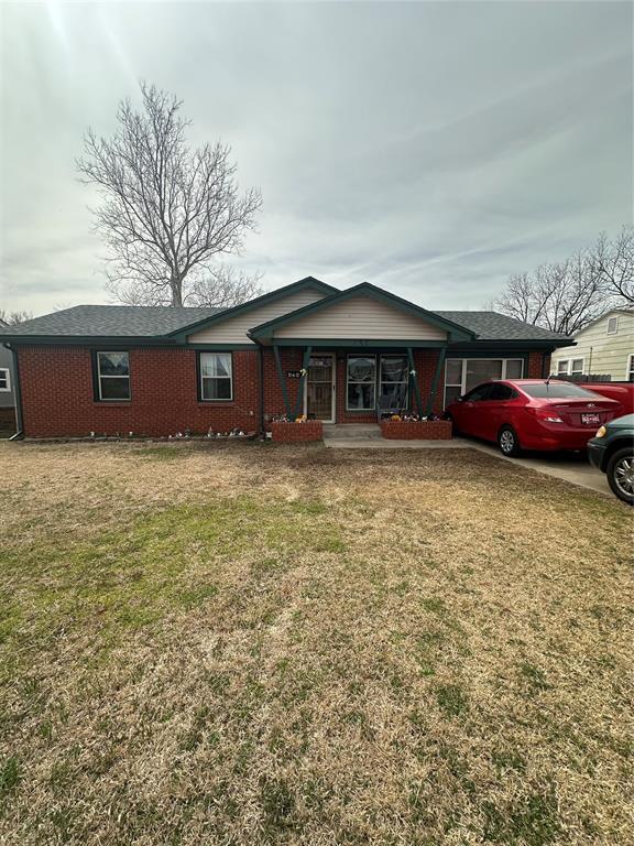 ranch-style house with a front yard and brick siding