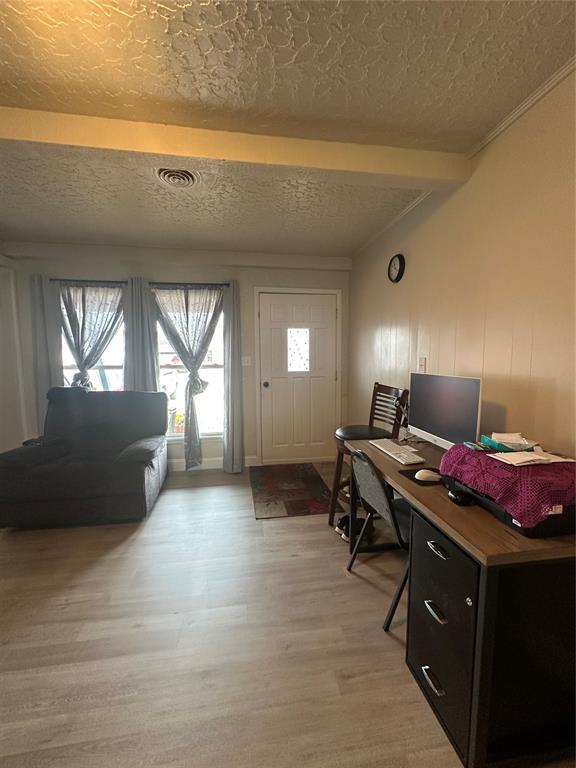 office space with visible vents, a textured ceiling, light wood-style flooring, and crown molding