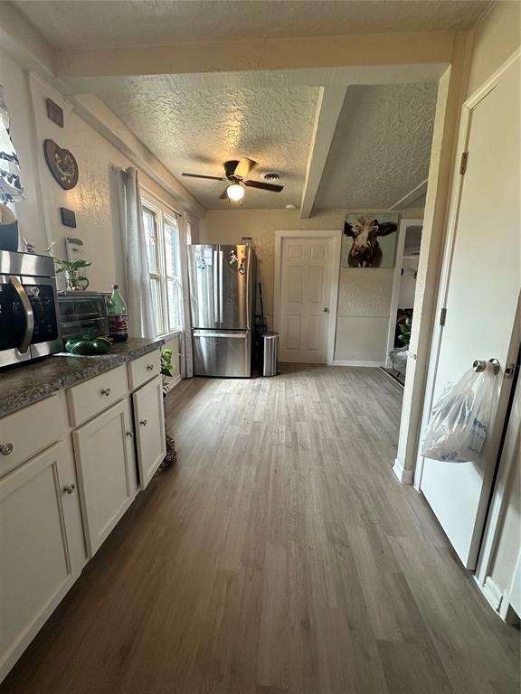 kitchen featuring stainless steel appliances, white cabinetry, light wood-style floors, and a textured ceiling