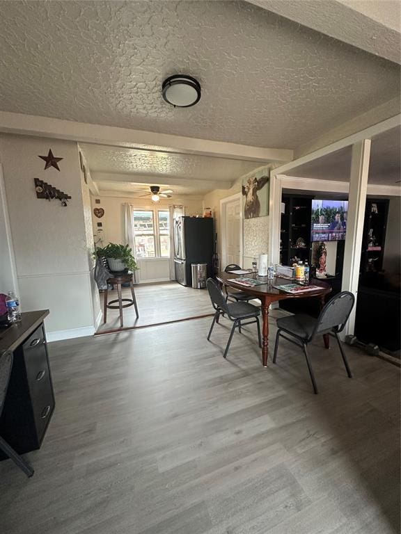 dining area with a textured ceiling, ceiling fan, wood finished floors, and baseboards