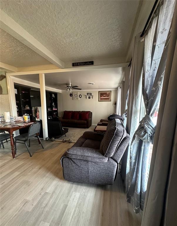 living area with a textured ceiling, wood finished floors, and a ceiling fan