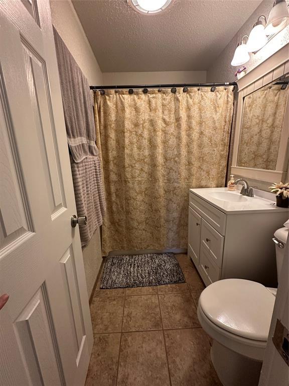 full bath with tile patterned floors, a textured ceiling, toilet, and vanity