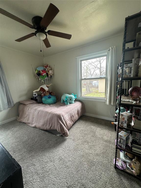 carpeted bedroom with ceiling fan and baseboards