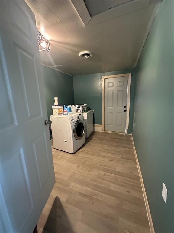 laundry area featuring laundry area, light wood finished floors, washing machine and clothes dryer, and baseboards