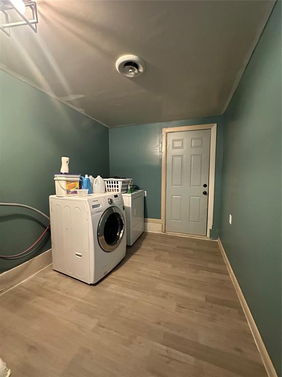 laundry room with laundry area, baseboards, wood finished floors, and washing machine and clothes dryer