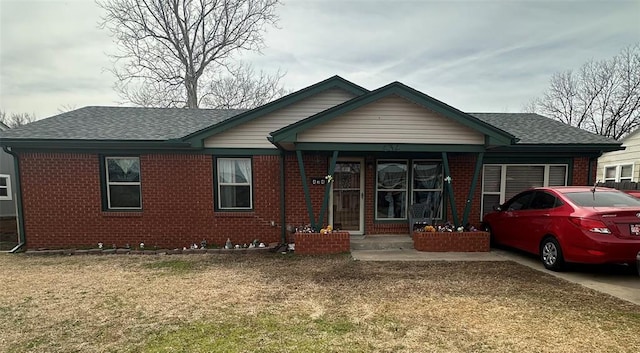 view of front facade featuring a garage, a shingled roof, a front yard, and brick siding