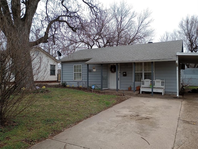 ranch-style house featuring driveway, a shingled roof, a front lawn, and an attached carport