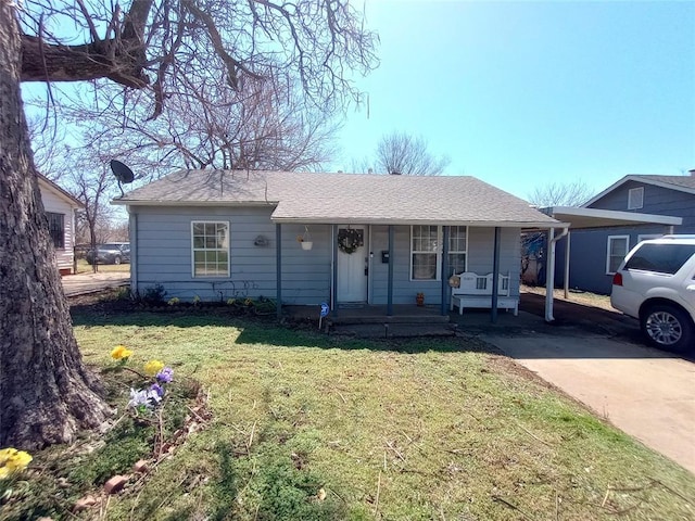 view of front facade with covered porch, roof with shingles, and a front yard