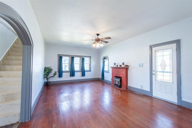709 S Broadway, Geary, OK 73040 - unfurnished living room featuring wood finished floors, a fireplace, arched walkways, and ceiling fan