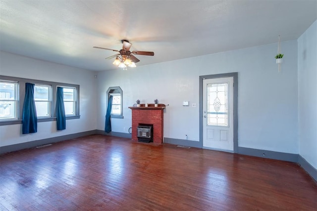 709 S Broadway, Geary, OK 73040 - unfurnished living room featuring plenty of natural light, ceiling fan, a fireplace, and hardwood / wood-style flooring