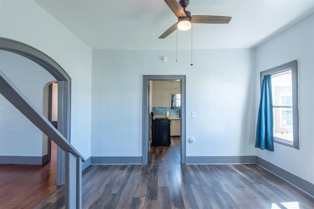 709 S Broadway, Geary, OK 73040 - spare room featuring baseboards, arched walkways, ceiling fan, and dark wood-style flooring