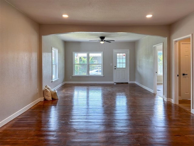 interior space with arched walkways, dark wood-type flooring, recessed lighting, and baseboards