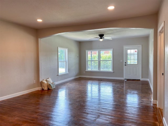 interior space with baseboards, dark wood-type flooring, and a healthy amount of sunlight