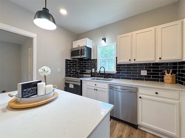 kitchen featuring backsplash, white cabinetry, stainless steel appliances, and a sink