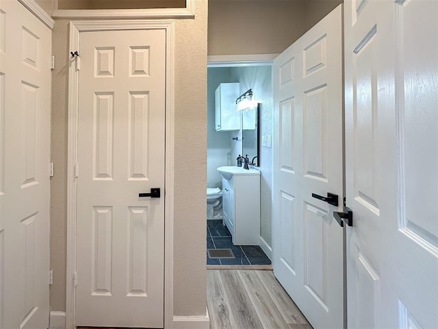 hall with a sink, baseboards, and wood finished floors