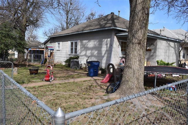 201 N Williams Ave, El Reno, OK 73036 - view of home's exterior with a trampoline, a fenced backyard, central AC unit, and roof with shingles