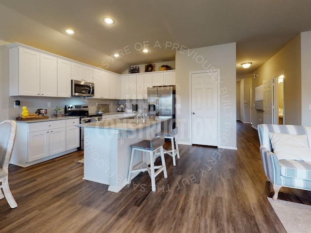 kitchen with light stone countertops, appliances with stainless steel finishes, white cabinets, and dark wood-style flooring