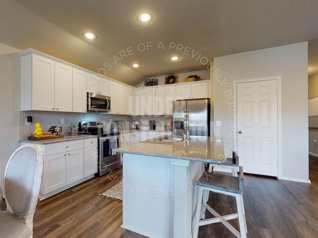 kitchen featuring lofted ceiling, white cabinetry, stainless steel appliances, and a sink