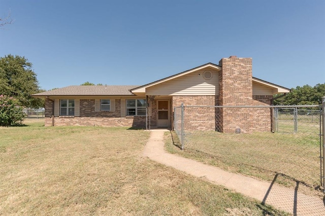 view of front of home featuring a gate, brick siding, fence, and a front lawn