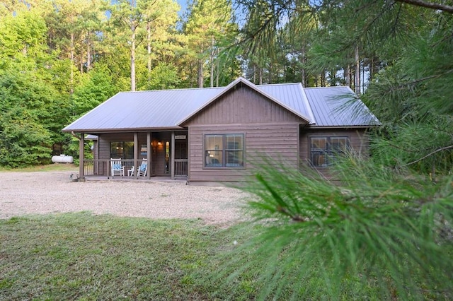 view of front of property featuring metal roof, a porch, and a front lawn