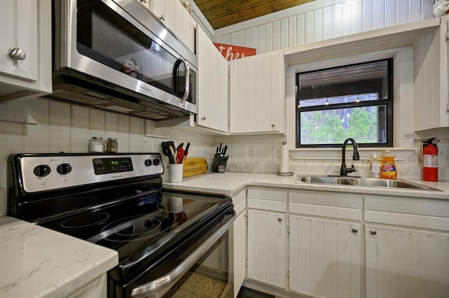 kitchen with appliances with stainless steel finishes, white cabinetry, light countertops, and a sink