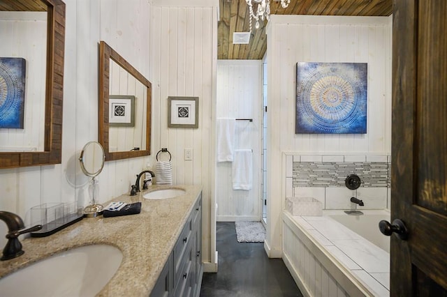 bathroom with double vanity, a garden tub, baseboards, and a sink