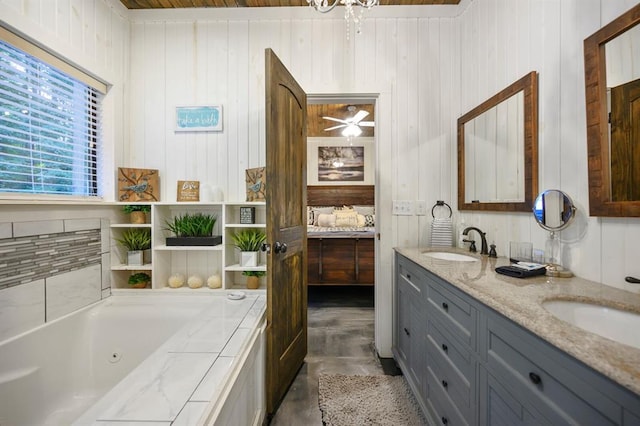 bathroom featuring a sink, a jetted tub, ceiling fan, and double vanity