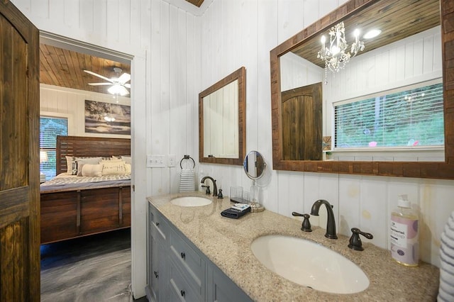 full bathroom with double vanity, ceiling fan with notable chandelier, ensuite bath, and a sink