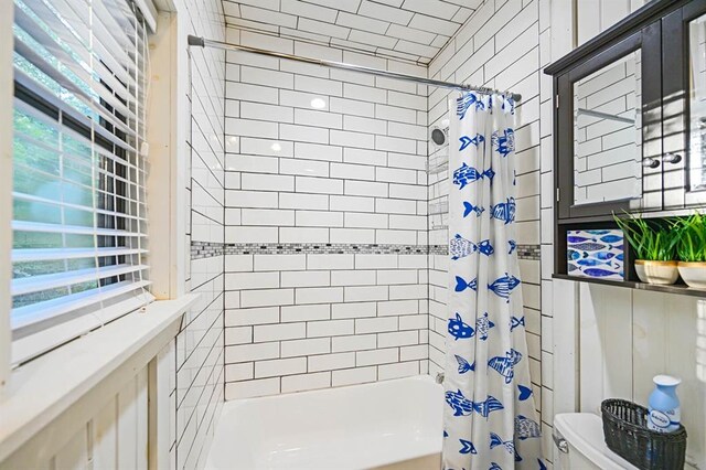 bathroom with toilet, a healthy amount of sunlight, and shower / bath combo with shower curtain