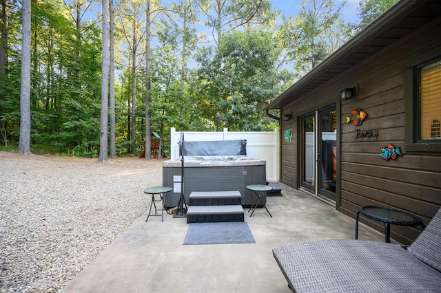 view of patio with a hot tub and fence