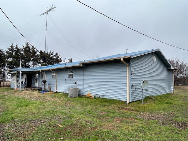 rear view of property with central AC and a lawn