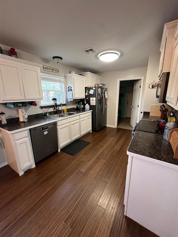 kitchen with stainless steel fridge, white cabinets, dishwasher, dark wood-type flooring, and a sink