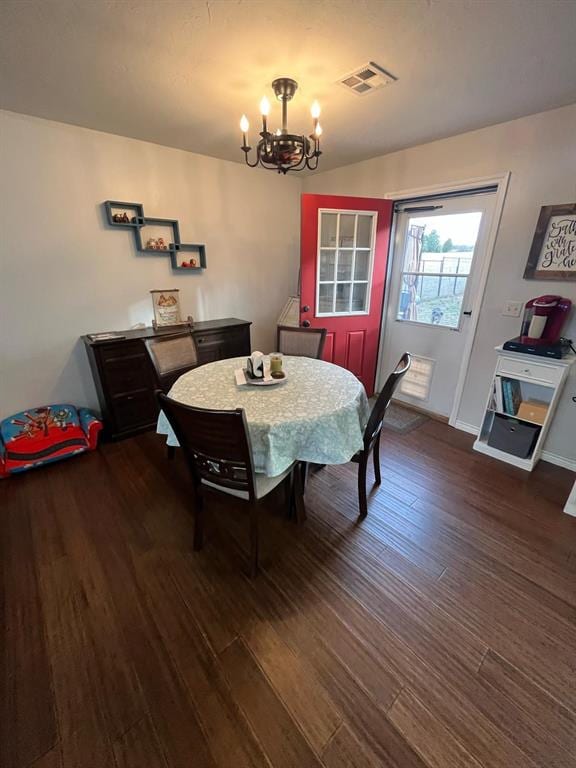 dining space with baseboards, wood finished floors, visible vents, and a notable chandelier